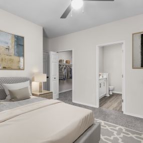 Bedroom with ensuite bath, ceiling fan, and walk-in closet