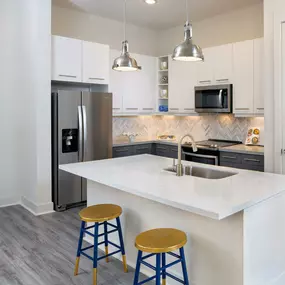 Kitchen with herringbone backsplash, stainless steel appliances, bar seating and white quartz countertops