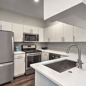 Kitchen with tile backsplash bottom freezer refrigerator quartz counters and stainless steel appliances