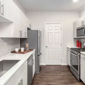 Kitchen with quartz countertops undermount sink tile backsplash and stainless steel appliances