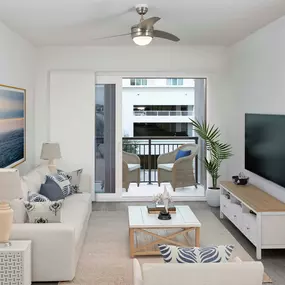 Living room with wood-inspired flooring, lighted ceiling fan, and balcony at Camden Lake Eola apartments in Orlando, FL