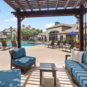 Covered poolside lounge area with seating and table at Camden Amber Oaks apartments in Austin, TX