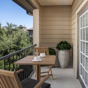 Private balcony with table and plants overlooking trees at Camden Amber Oaks apartments in Austin, TX