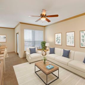 Living room with dark crown molding and ceiling fans