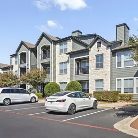 Apartment building exterior with parking spaces out front at Camden Amber Oaks apartments in Austin, TX