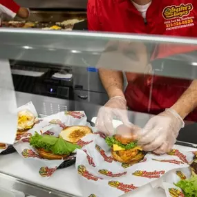 A Taystee's Burger employee making food