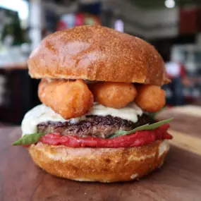 Mac Attack burger at Taystee's in Dearborn - American cheese, Mac N Cheese Bites, coleslaw, tomato, Taystee's Spicy Mayo on a brioche bun.