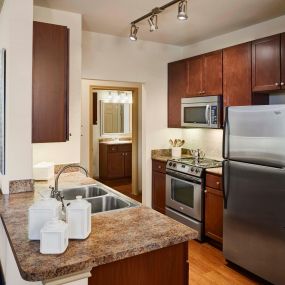 Neighborhood two kitchen with stainless steel appliances track lighting and wood look flooring