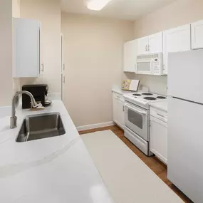 Neighborhood one kitchen with white appliances electric cooktop and wood look flooring