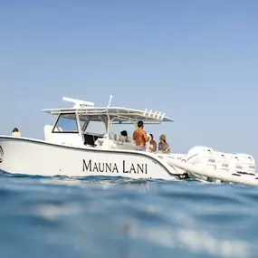 White boat with “Mauna Lani” written on the side on calm blue water.