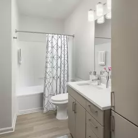 Contemporary finish style features mocha matte cabinets and white quartz countertops and large soaking bathtub.