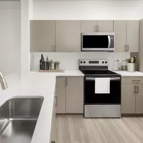 Kitchen with stainless steel appliances, mocha cabinetry, and quartz countertops at Camden Westwood apartments in Morrisville, NC