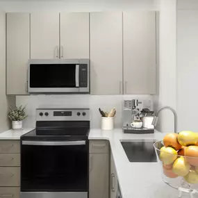 Kitchen with tile backsplash, stainless steel appliances, and glass cooktop at Camden Westwood apartments in Morrisville, NC