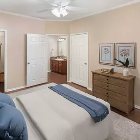 Bedroom with walk-in closet, ensuite, and patio access with wood-style flooring throughout.