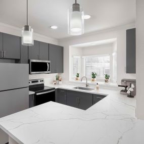 Kitchen with marbled white quartz countertops, dark gray cabinets and stainless steel appliances at Camden Legacy Park