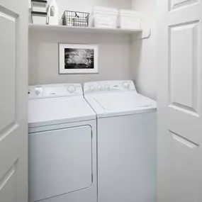 Laundry closet with full size washer and dryer and built-in shelf at Camden Legacy Park apartments in Plano, TX