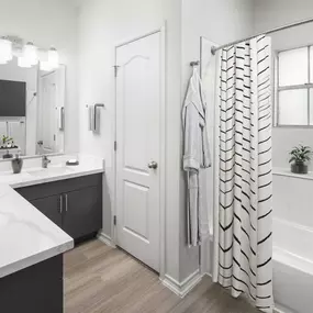 Newly renovated bathroom with marble-style quartz countertops and bathtub at Camden Legacy Park apartments in Plano, TX