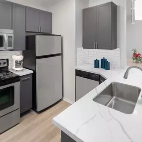 Kitchen with marble-style quartz countertops, gray cabinetry and stainless steel appliances