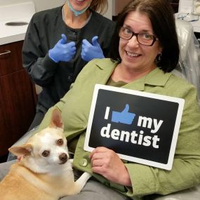 Happy customer enjoying her time at the dentist with her dog.