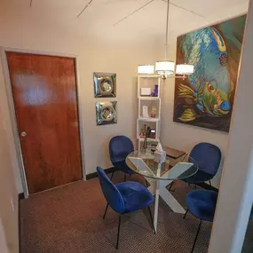Small room with glass table and four blue chairs