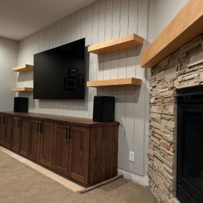 Embrace simplicity with a Walnut entertainment center and Douglas Fir floating shelves – a cozy addition to your home