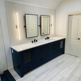 Custom inset naval bathroom vanity with seeded glass & white herringbone backsplash.