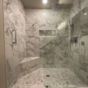 Custom Aging in Place walk in shower with Marble Attache tile. Grab bars, custom shower bench, body sprays, handheld wand, and rain shower head. Luxury shower!