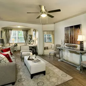 Living room with wood-look flooring, ceiling fan, and solarium with space for a home office