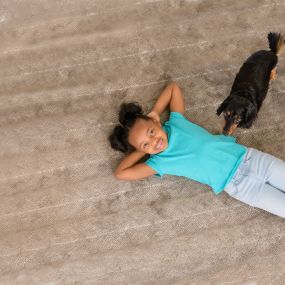 girl and dog lying on carpet