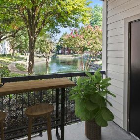 Private balcony with storage closet and hightop table overlooking community lake at Camden Buckingham apartments in Richardson, TX