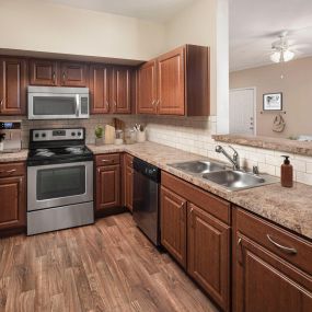 Kitchen with stainless steel appliances and bar-height countertops at Camden Buckingham apartments in Richardson, Tx