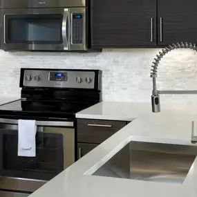 Enjoy your kitchen by using a pull down spray faucet in your single basin stainless steel sink and your ceramic stovetop at Camden Brickell Apartments in Miami, FL.