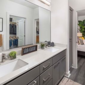 Camden Tempe West Apartments in Tempe Arizona ensuite luxurious contemporary bathroom with dual sink vanity white quartz countertop and gray cabinetry and wood-like flooring
