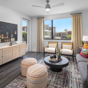 Camden Tempe West Apartments in Tempe Arizona contemporary living room with gray wood-like flooring,  lighted ceiling fan spacious window near patio