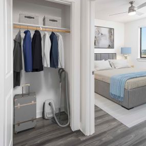 Camden Tempe West Apartments Tempe Arizona contemporary main bedroom with lighted ceiling fan and gray woodlike flooring next to coat hallway closet with wooden shelves and rods