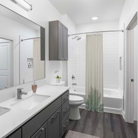 Camden Tempe West Apartments Tempe Arizona contemporary bathroom with gray cabinets, white shaker cabinets wood-like flooring and plenty of storage and curved shower rods