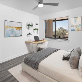 Camden Tempe West Apartments Tempe Arizona contemporary spacious main bedroom with room for a home office an king size bed under a lighted ceiling fan next to a large window near the patio