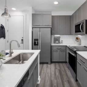 Camden Tempe West Apartments Tempe Arizona contemporary kitchen with gray cabinets and white quartz countertops with stainless steel appliances and side-by-side refrigerator