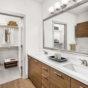 Bathroom with dual vanity sinks walk in closet and framed mirrors