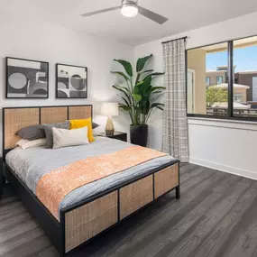 Camden Tempe West Apartments in Tempe Arizona contemporary main bedroom with lighted ceiling fan gray woodlike flooring and expansive window