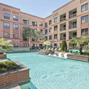 Resort style pool with greenery surround and in the water sun loungers at Camden Travis Street Apartments in Midtown Houston, Tx