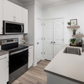 Renovated kitchen with white cabinets and beige grey quartz countertops at Camden Shadow Brook apartments in Austin, TX