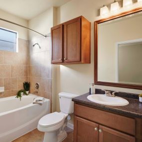 Bathroom with bathtub with tile surround and curved shower rod tile floors and framed mirror