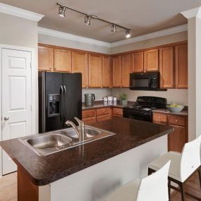 Kitchen with dark countertops and island at Camden Shadow Brook