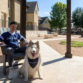 Resident sitting with their dog in the dog park at Camden Shadow Brook