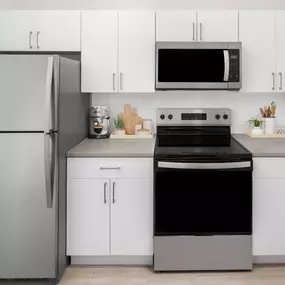 Kitchen with white, flat-front cabinets, taupe countertops, stainless steel appliances, and white subway tile backsplash at Camden Shadow Brook apartments in Austin, TX