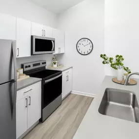 Kitchen with white cabinets, taupe countertops, and deep-basin sink with pull-down sprayer faucet at Camden Shadow Brook apartments in Austin, TX