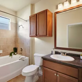 Bathroom with bathtub with tile surround and curved shower rod tile floors and framed mirror