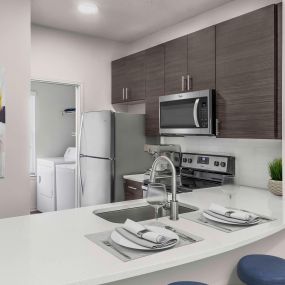 Townhome floor plan kitchen alongside laundry room with full size washer and dryer and shelving