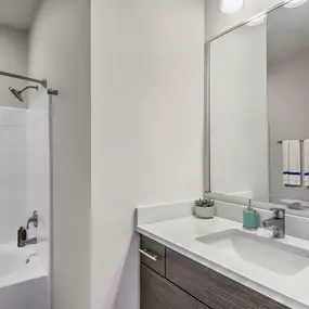 Townhome bathroom with quartz countertop and bathtub with curved shower rod and rainfall showerhead